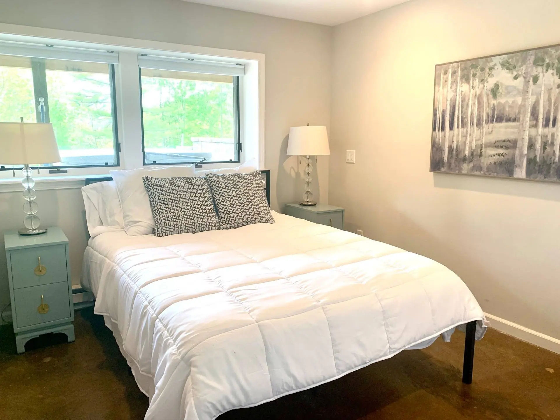 Bedroom with white bedding and a wooded view